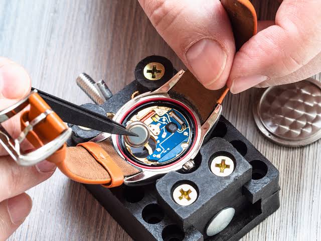 Watchmaker tools, precision parts and a timepiece arranged on a repair bench